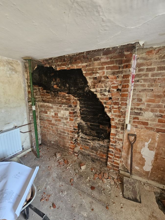 Brick fireplace opened up behind later plaster